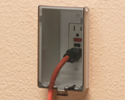 extension cord plugged into outdoor electrical box with cover closed