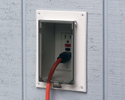 extension cord plugged into outdoor electrical box with cover closed