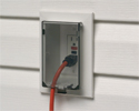 extension cord plugged into outdoor electrical box with cover closed