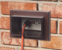 extension cord plugged into outdoor electrical box with cover closed