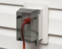 extension cord plugged into outdoor electrical box with cover closed