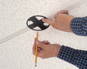 person tracing cutout for box on ceiling tiles