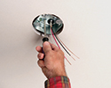 person tightening ceiling box with screwdriver