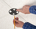 person marking where to cut ceiling tiles to mount box