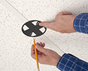 person marking where to cut ceiling tiles to mount box