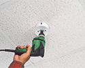 person using hole saw to make hole in ceiling tile