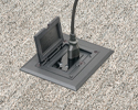 Single gang floorbox installed in carpeted floor with device plugged into receptacle