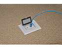 floor box in carpeted floor with device plugged in