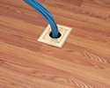 floor box in wooden floor with bundle of cables routed into floor box