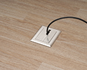 floor box in wooden floor with device plugged in and routed through slotted cover