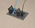 floor box in carpeted floor with devices plugged in