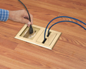 person plugging device into floor box receptacle