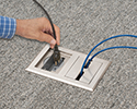 person plugging device into floor box receptacle