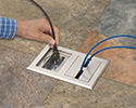 person plugging device into floor box receptacle