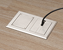 two gang floor box in wooden floor with device plugged in