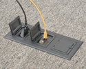 Three gang floorbox installed in carpeted floor with device and ethernet plugged in