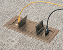 Three gang floorbox installed in carpeted floor with device and ethernet plugged in