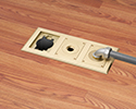 three gang floor box in wooden floor with 90 degree connector and conduit attached