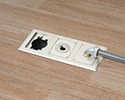 three gang floor box in wooden floor with 90 degree connector and conduit attached