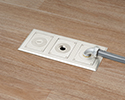 three gang floor box in wooden floor with 90 degree connector and conduit attached