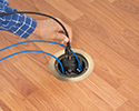 person plugging device into floor box receptacle