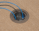 in-box recessed floor box in carpeted floor with devices plugged in