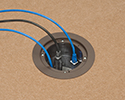 in-box recessed floor box in tiled floor with devices plugged in