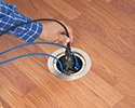 person plugging device into floor box receptacle