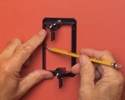 person tracing inside of bracket on wall where bracket will be installed