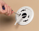 person securing smoke detector mounting bracket to low voltage mounting bracket