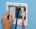 person installing low voltage divider in three gang box